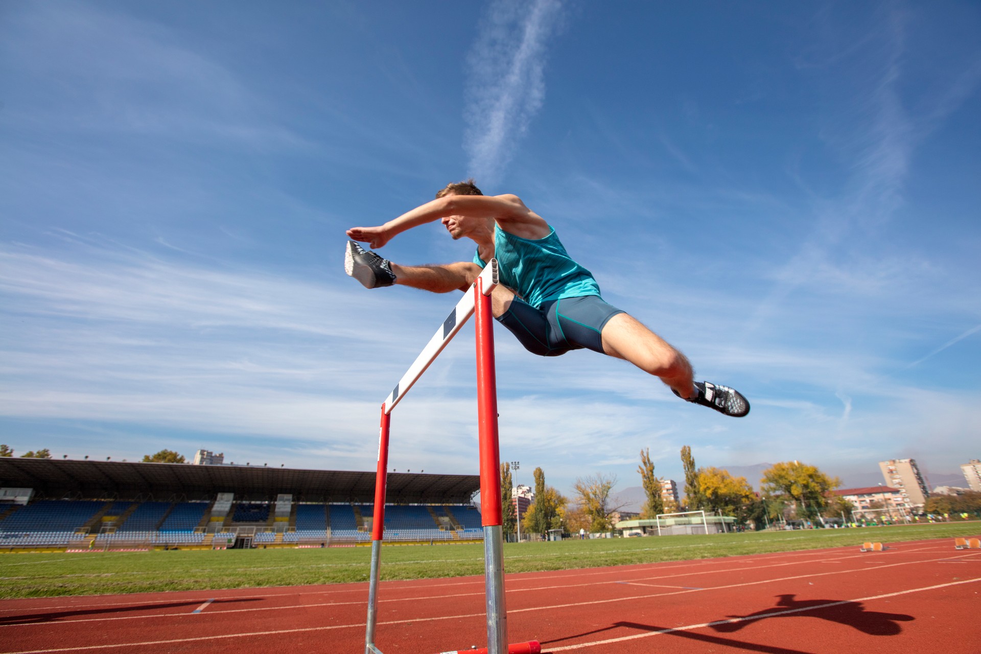 Low angle view of determined male athlete jumping over a hurdles